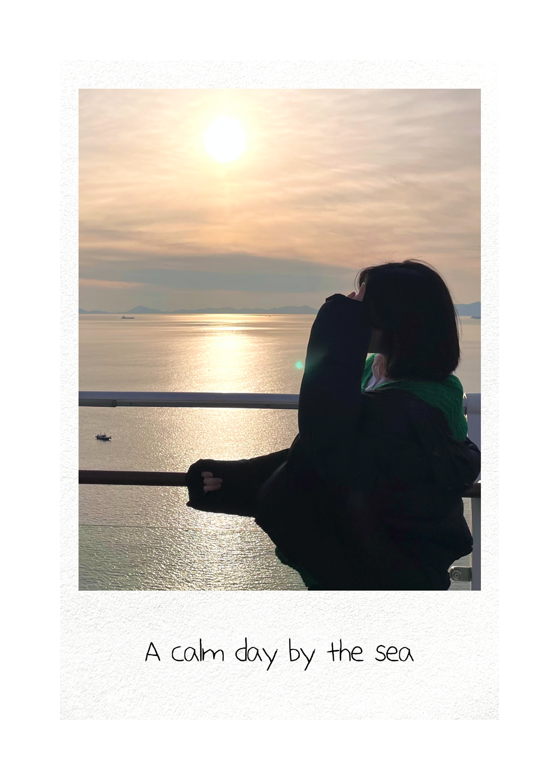 A polaroid card of a person watching the sunset over the sea with the handwritten caption A calm day by the sea